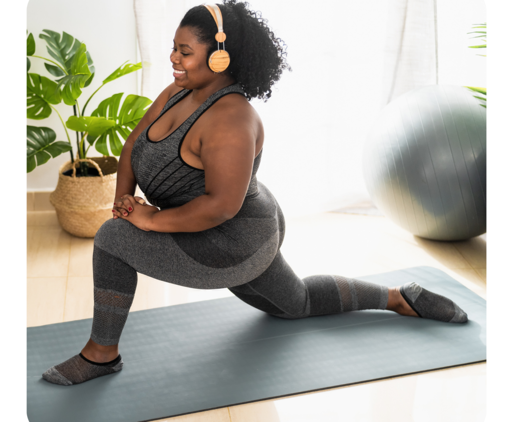 woman with yellow over the ear headphones stretching on a yoga mat.